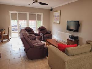 a living room with couches and a flat screen tv at The Manse in Queenscliff