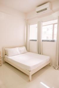 a white bed in a room with a window at Urban Nest with a View in Iloilo City