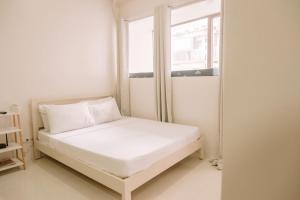 a small white bed in a room with a window at Urban Nest with a View in Iloilo City