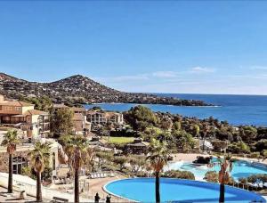 a resort with two pools and palm trees and the ocean at Appartement LES PETITS PRINCES in Agay - Saint Raphael