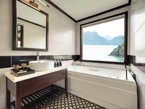uma casa de banho com um lavatório, uma banheira e uma janela em Le Journey Elegance Cruise em Ha Long mais 34 fotografias