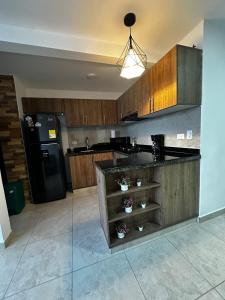 eine Küche mit Holzschränken und einem schwarzen Kühlschrank in der Unterkunft Apartamento con hermosa vista en Barranquilla in Puerto Colombia