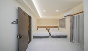 a bedroom with two beds and a door in it at Hualien Leo and Alley Elevator B&B in Hualien City