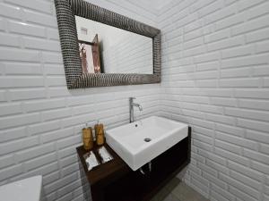 a white bathroom with a sink and a mirror at Nirun Garden Villa - Balinese Traditional House in North Bali in Ambengan +14 photos