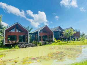 une maison avec un étang devant dans l'établissement Chom Nakhon Resort, à Tha Sala