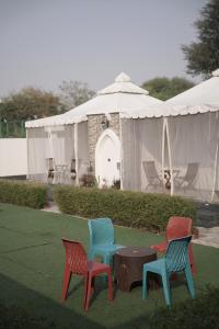 KālwāraChandraprabha Signature Resort Jaipur的四把五颜六色的椅子和一张帐篷前的桌子