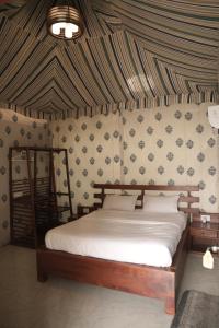 KālwāraChandraprabha Signature Resort Jaipur的一间卧室配有一张带条纹墙的床