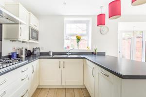 a kitchen with white cabinets and a black counter top at Home away from Home French luxury in Birmingham in Birmingham +25 photos