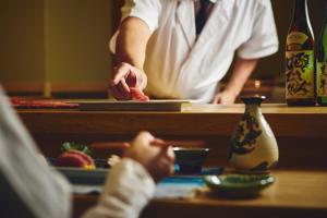 a man standing at a counter with a plate of food at ANA InterContinental Manza Beach Resort by IHG in Onna