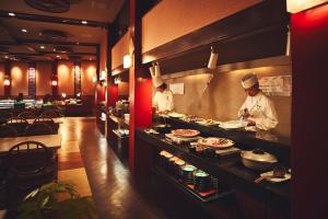 two chefs preparing food in a restaurant kitchen at ANA InterContinental Manza Beach Resort by IHG in Onna
