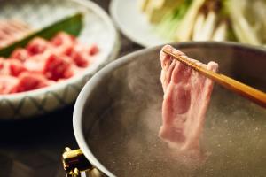 a piece of meat in a pan with a pair of chopsticks at ANA InterContinental Manza Beach Resort by IHG in Onna