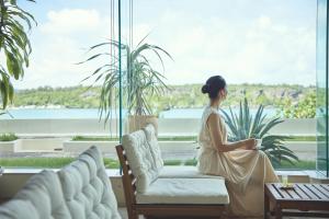 a woman sitting on a couch in front of a window at ANA InterContinental Manza Beach Resort by IHG in Onna +37 photos