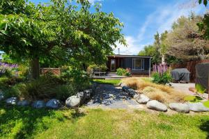 a backyard with a house with a tree and rocks at Private Rooms with Shared Bathroom in Lake Tekapo