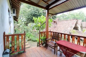 Una terraza de madera con un banco y una mesa. en Penginapan Widodo Syariah Borobudur, en Magelang