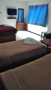 a hotel room with two beds and a television at Asoka Inn in Mettuppālaiyam +3 photos