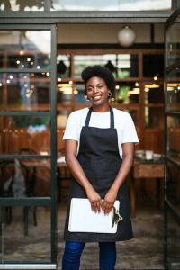 a woman in a black apron holding a box at Riyadh Barista Training School Nansana Uganda in Kampala