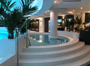 a swimming pool in a hotel with stairs and plants at Hanza Tower Apartments Premium in Szczecin