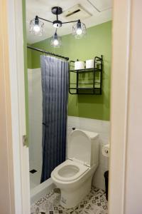 a bathroom with a toilet with a blue shower curtain at Cozy Davao Studio with Queen and Bunk Bed Near Abreeza Mall in Davao City +21 photos