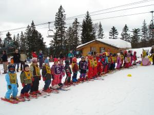 a group of children are lined up on skis in the snow at Chalet Monts Jura in Mijoux