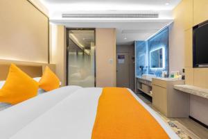 a bedroom with a bed with orange pillows and a television at 天门山云尚景豪酒店 in Zhangjiajie