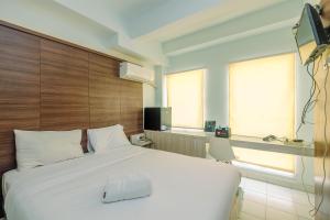 Un dormitorio con una cama blanca y un televisor. en Nice and Cozy Studio Apartment at Patraland Urbano By Travelio, en Bekasi