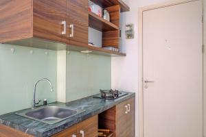 Una cocina con fregadero y armarios de madera. en Nice and Cozy Studio Apartment at Patraland Urbano By Travelio, en Bekasi