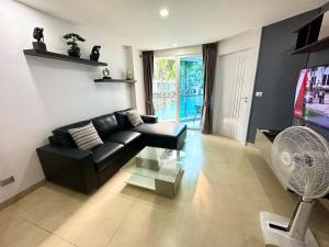 a living room with a black couch and a tv at Large luxury condo - Pattaya City Centre - Centara Avenue, Pool View - 217 in Pattaya Central