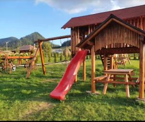 een speeltuin met een rode glijbaan en een bank bij Poiana Bucovineana in Poiana Negrii