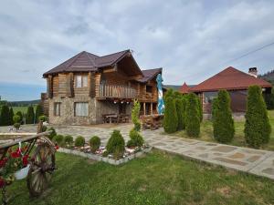 een blokhut met een veranda en een tuin bij Poiana Bucovineana in Poiana Negrii