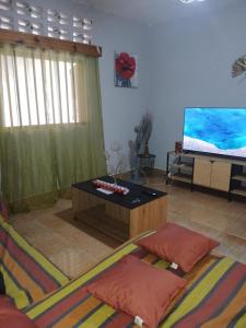 a living room with a table and a tv at AMI LODGE in Mamoudzou +6 photos