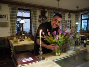 Ein Mann steht hinter einem Tresen mit einer Vase Blumen. in der Unterkunft Hotel Engel in Endingen
