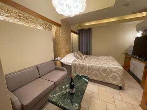 ein Wohnzimmer mit Sofa und Bett in der Unterkunft hotel evi tower 大人専用 in Toda