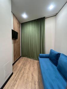 a living room with a blue couch and a green curtain at 2- комнатные апартаменты люкс в ЖК Арайлы in Aktobe +18 photos