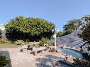 un patio con tavolo e panca in un cortile di Wildecrest & Ripplemead, Amblewood Guesthouse a Kenton-on-Sea