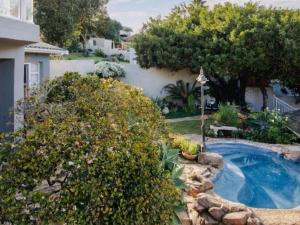 a backyard with a swimming pool and some bushes at Treetops, Amblewood Guesthouse in Kenton on Sea