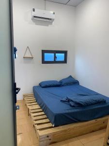 Un dormitorio con una cama con sábanas azules y una ventana. en Homestay TT House, en Chợ Phước Hải