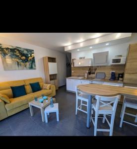 Una sala de estar con un sofá y una mesa y una cocina. en Appartement cosy mer, en Le Grau-du-Roi