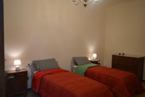 a bedroom with two beds with red blankets and a dresser at Bellavista apartment in Bagni di Lucca