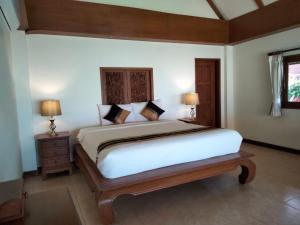 a bedroom with a large bed and two lamps at MJ Beautiful sunset beach house in Ban Na We +42 photos