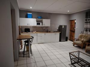 a kitchen with white cabinets and a table and a refrigerator at Self catering apartment in Vereeniging