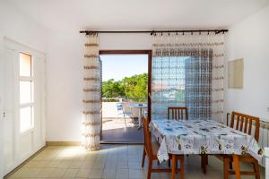 a dining room with a table and a balcony at Bady Apartments with BBQ in Novalja