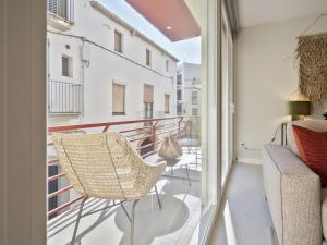 a balcony with a rattan chair and a couch at Sitges Spaces Deluxe Comfort Flat-Monthly Rentals in Sitges