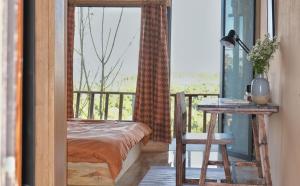 a bedroom with a bed and a table and a window at Nhà Đậu Homestay Măng Đen - 75 Võ Thị Sáu in Kon Plong