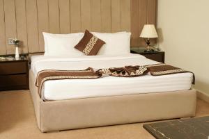 a bedroom with a large bed with white sheets and pillows at Falettis Express Islamabad in Islamabad