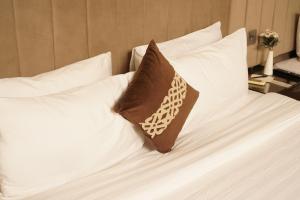a brown pillow sitting on a white bed with white pillows at Falettis Express Islamabad in Islamabad +20 photos