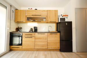 a kitchen with wooden cabinets and a black refrigerator at Résidence Les Esserts - Les Esserts MAE-3931 in Les Houches