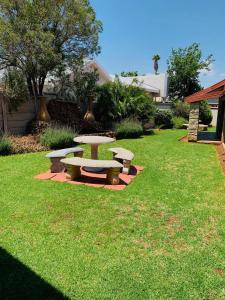 a picnic table and benches in a yard at Leruo's Guest House in Kimberley