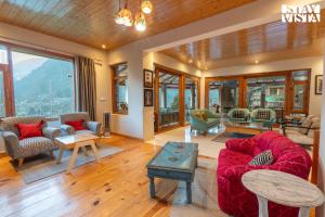 a living room with a red couch and chairs at Stayvista at Tulip Terraces Cozy Mountain Home with Fireplace in Manāli