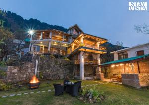 a house with a fire pit in the yard at Tulip Terraces by VEO - Part of StayVista in Manāli