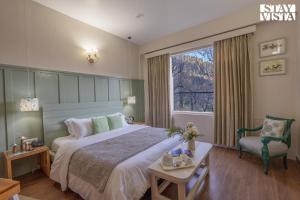 a bedroom with a bed and a chair and a window at Stayvista at Tulip Terraces Cozy Mountain Home with Fireplace in Manāli